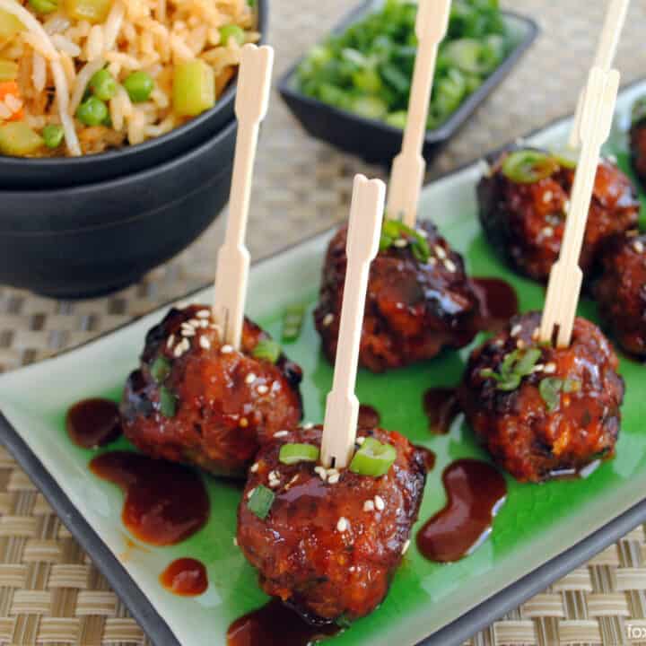Gochujang meatballs on rectangle platter, with toothpick inserted into each meatball.