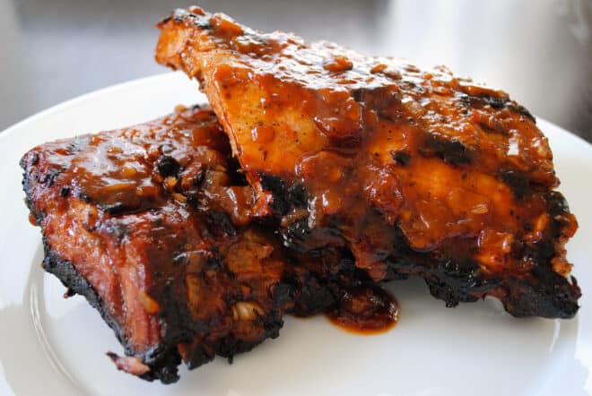 Two half racks of root beer ribs on a white plate.