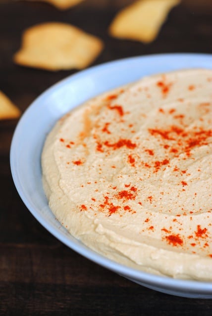 Closeup photo of hummus topped with paprika in light blue bowl.