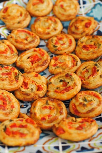 Baked puff pastry pinwheels filled with savory filling on festive platter.