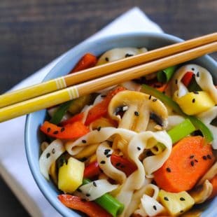 Asian stir fry with noodles in blue bowl with chopsticks.