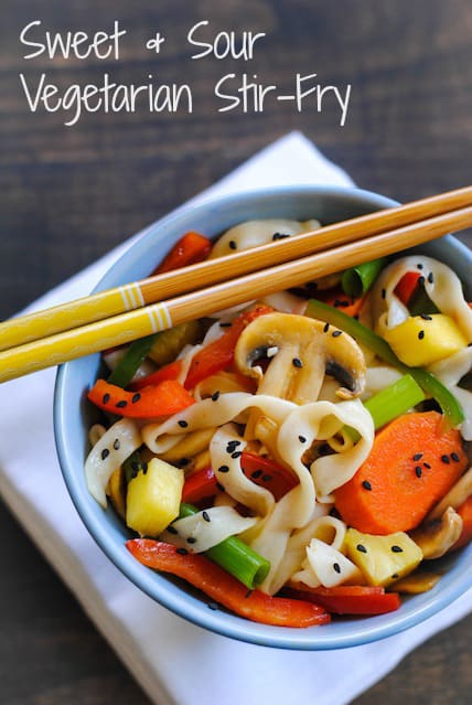 Stir fried vegetables and noodles in blue bowl with yellow accented chopsticks resting on top. Overlay: Sweet + Sour Vegetarian Stir-Fry