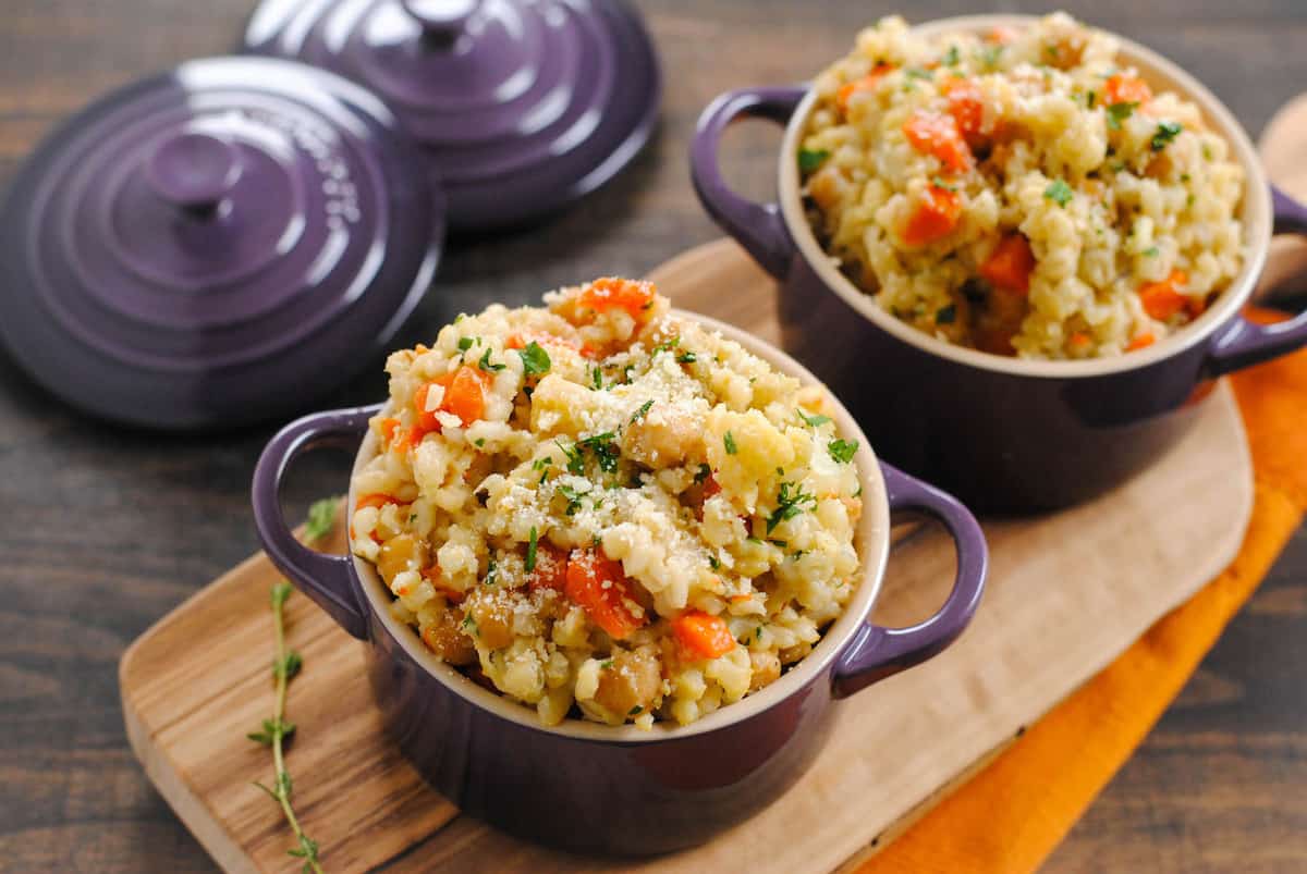 Slow cooker barley risotto in small purple cocottes with lids.