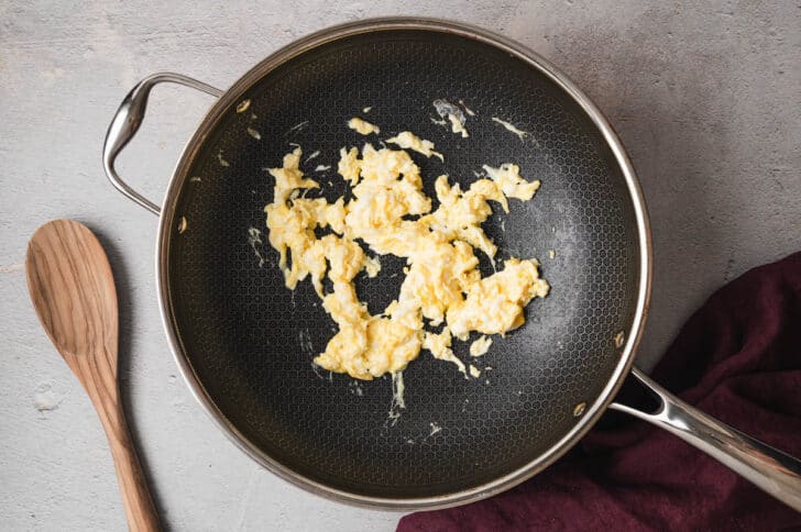 A dark nonstick skillet filled with scrambled eggs.