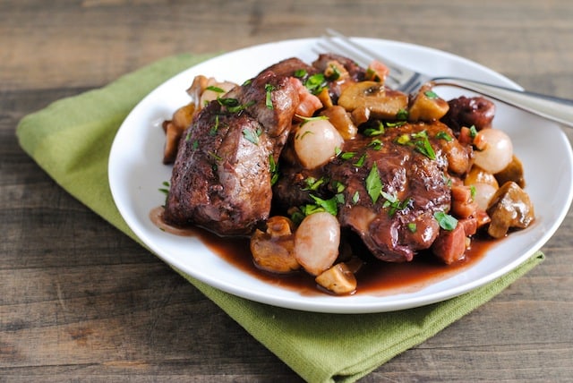Classic Coq au Vin - Chicken, pancetta, mushrooms and pearl onions braised in red wine. Comfort food at it's finest. Perfect for a dinner party! | foxeslovelemons.com