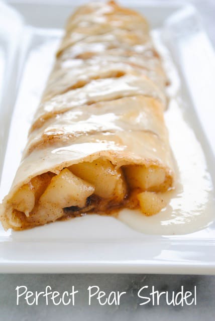 Cooked pears wrapped in phyllo dough, with glaze, on rectangular white plate with "Perfect Pear Strudel" overlay at bottom.