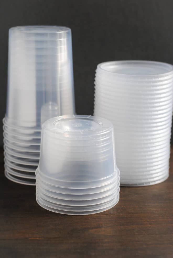 Plastic takeout containers to be used for freezer meals, on a wooden surface.