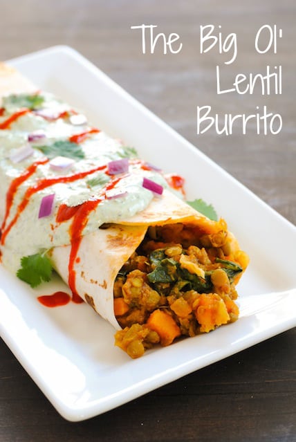 Big burrito filled with lentils and sweet potatoes on rectangular white plate. Overlay: The Big Ol' Lentil Burrito
