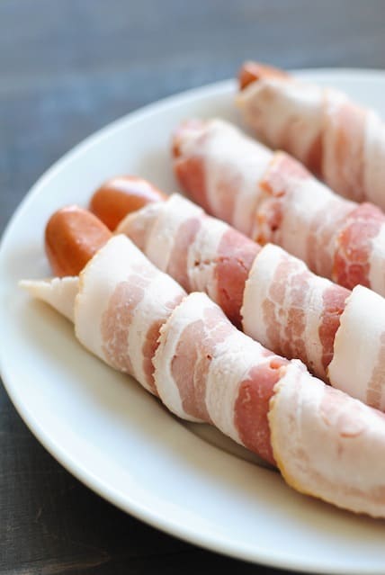 Frankfurters wrapped with raw bacon.