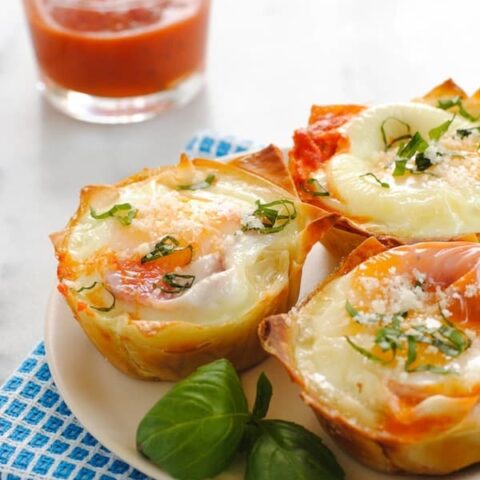 Italian Egg Wonton Cups - A cute, delicious way to serve eggs to a crowd at brunch! Crispy wonton cups filled with marinara sauce and eggs, topped with Parmesan cheese and basil. | foxeslovelemons.com