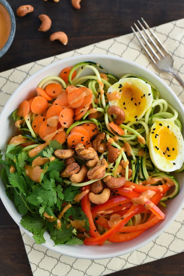 Zucchini Noodle Bowl with Spicy Cashew Sauce - Spiralized zucchini topped with carrots, red pepper, cilantro, a soft-boiled egg and an Asian-inspired spicy cashew sauce. | foxeslovelemons.com