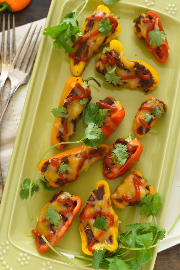 Black Bean Stuffed Mini Pepper Bites - A protein-packed snack, or fun party appetizer! Mini bell peppers stuffed with refried black beans and topped with cheese. | foxeslovelemons.com