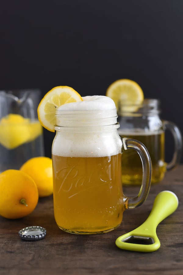 Wheat beer shandy in glass mug with lemons in background.