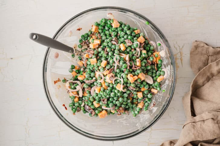 A glass bowl filled with a recipe for pea salad.