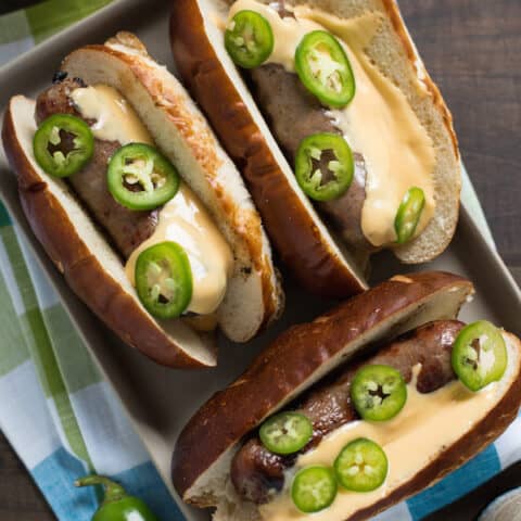 Beer Brats with Beer Queso - For the beer and grilling lovers in your life! Beer-flavored bratwurst topped with a sharp cheddar-beer queso. Serve with beer! | foxeslovelemons.com