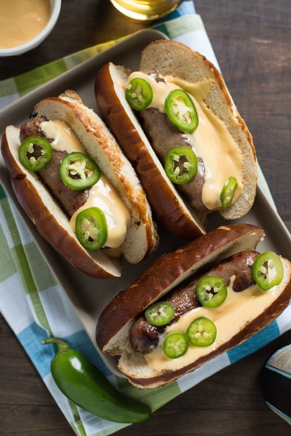 Beer Brats with Beer Queso - For the beer and grilling lovers in your life! Beer-flavored bratwurst topped with a sharp cheddar-beer queso. Serve with beer! | foxeslovelemons.com