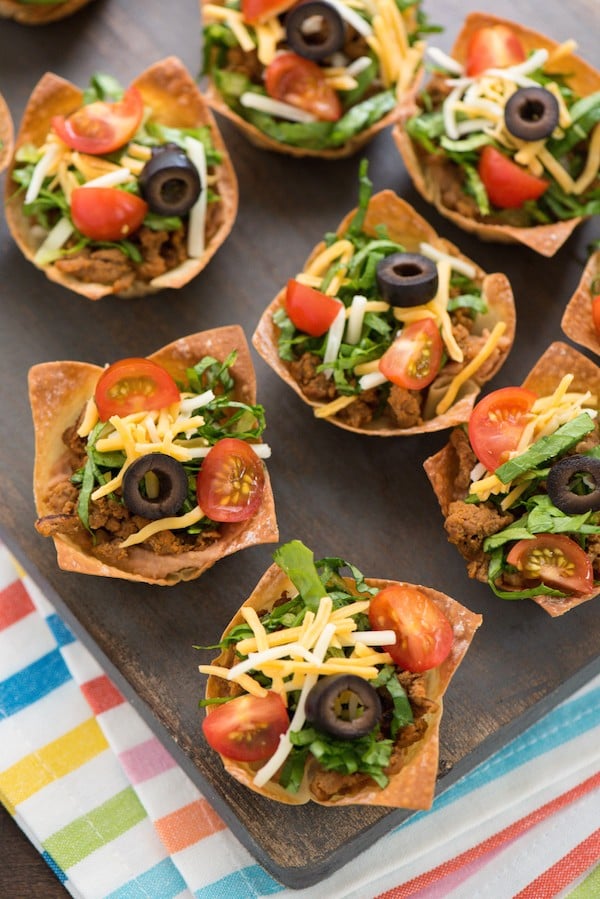 Mini Turkey Taco Salads - An appetizer-sized version of the restaurant classic! Layers of beans, seasoned ground turkey, cheese, lettuce and tomato inside of wonton wrapper "taco shell" bowls! | foxeslovelemons.com