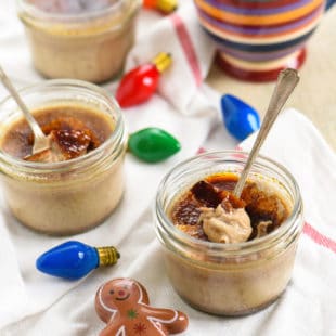 Small mason jars of gingerbread creme brulee with christmas decorations.