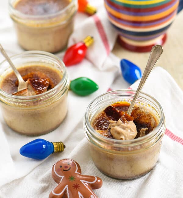 Small mason jars of gingerbread creme brulee with christmas decorations.