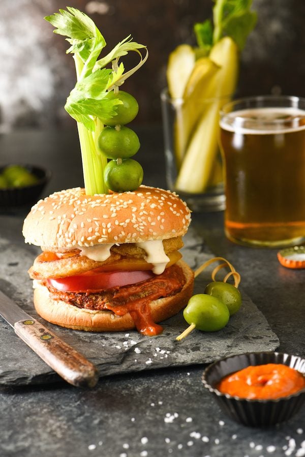 Epic Bloody Mary Burgers - Bloody mary lovers, this burger is calling your name! The burger is slathered in bloody mary ketchup, then topped with onion rings, tomato slices and horseradish mayo. Skewer with celery, olives and pickles and dig in! | foxeslovelemons.com