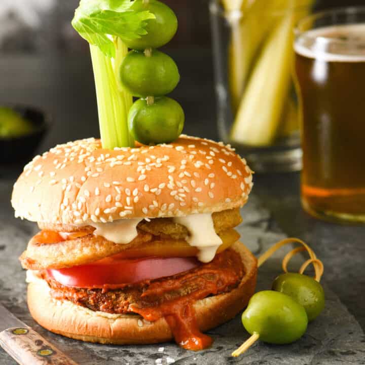 Epic Bloody Mary Burgers - Bloody mary lovers, this burger is calling your name! The burger is slathered in bloody mary ketchup, then topped with onion rings, tomato slices and horseradish mayo. Skewer with celery, olives and pickles and dig in! | foxeslovelemons.com