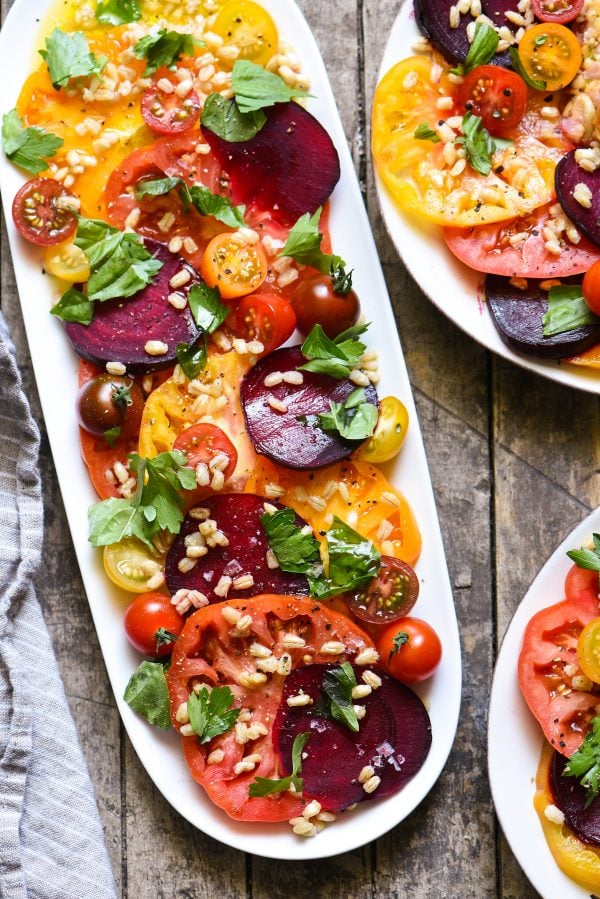 Oblong platter of tomatoes, beets, barley and torn herbs.