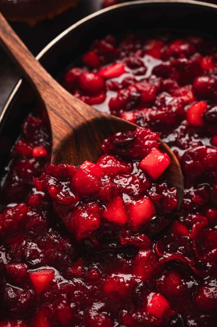 A recipe for cranberry sauce, with a wooden spoon digging into it.