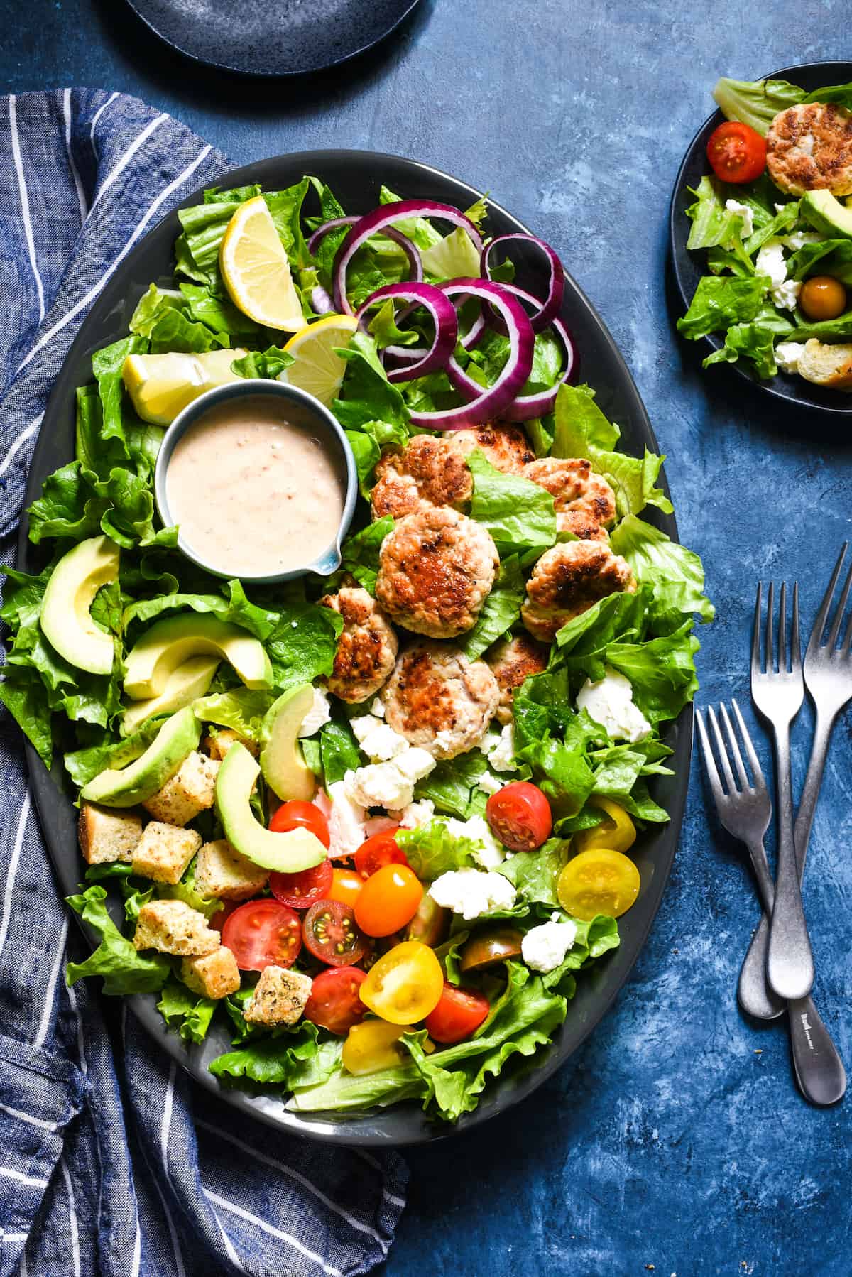 Large platter of ground turkey salad on blue surface with forks.