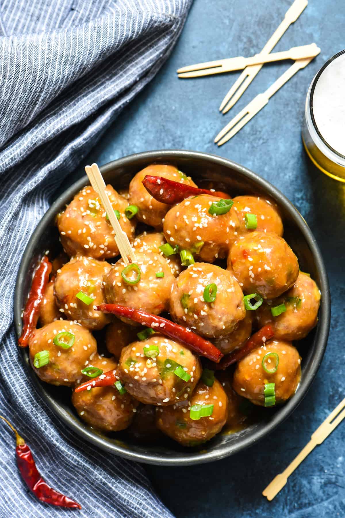 Chinese meatballs being served in a party tablescape, with toothpicks and beer.