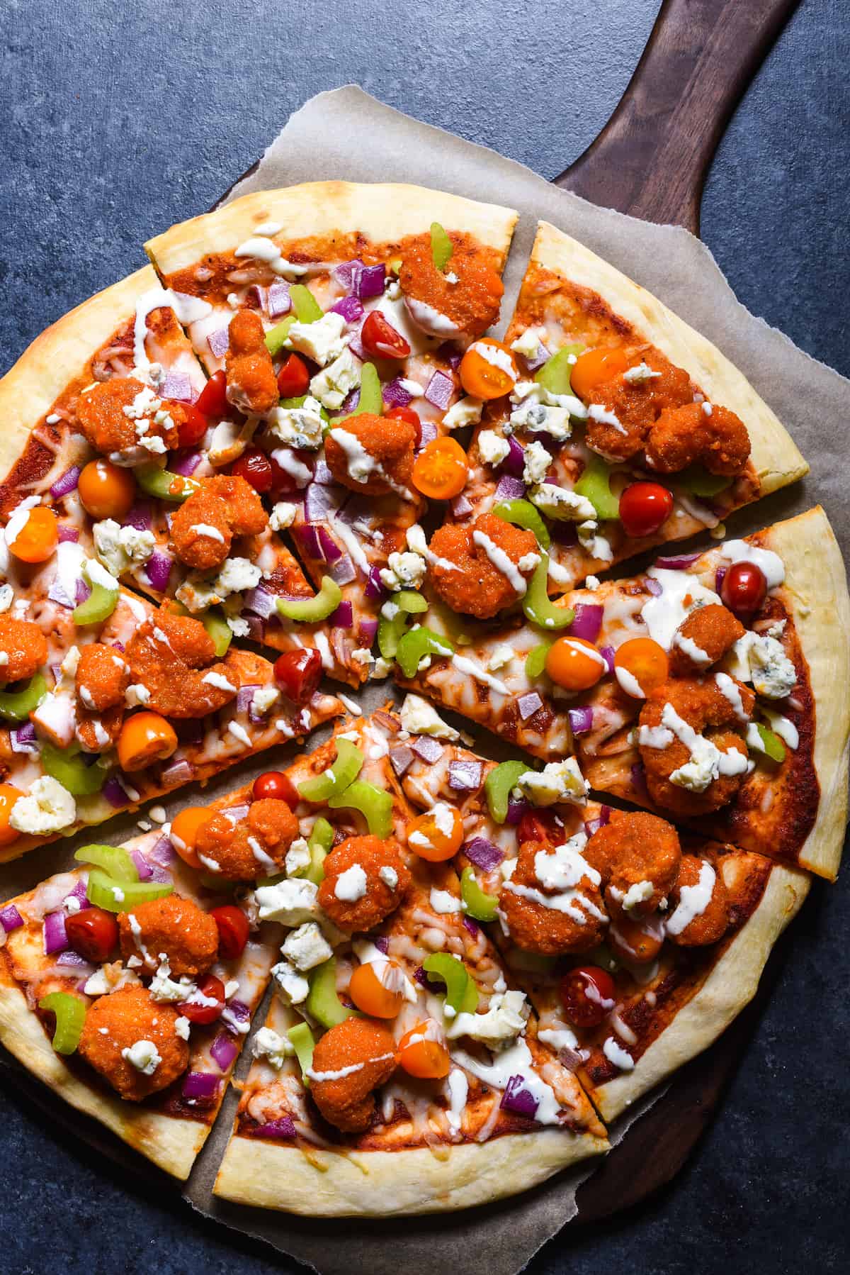 Buffalo shrimp pizza garnished with vegetables, blue cheese and ranch dressing.