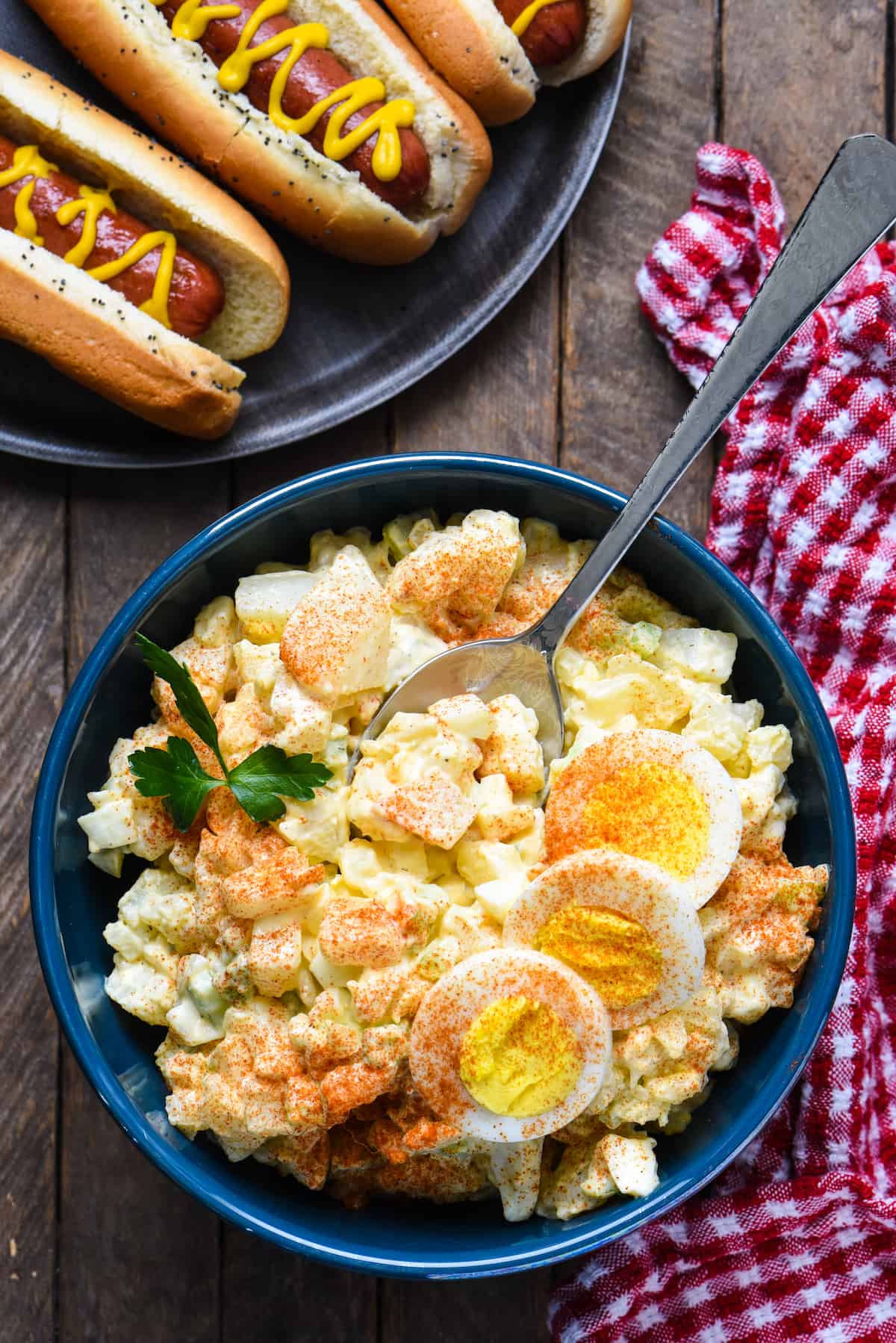 A blue bowl filled with potato salad with egg.