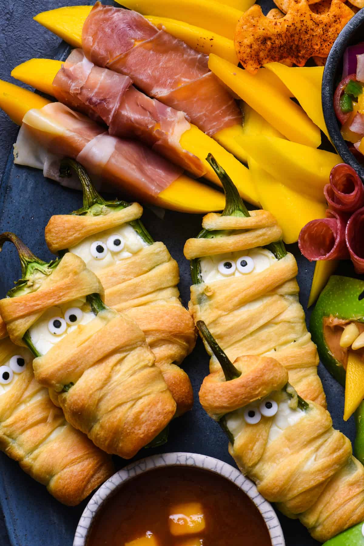 Closeup photo of Halloween food ideas, like jalapeno poppers wrapped up like mummies.