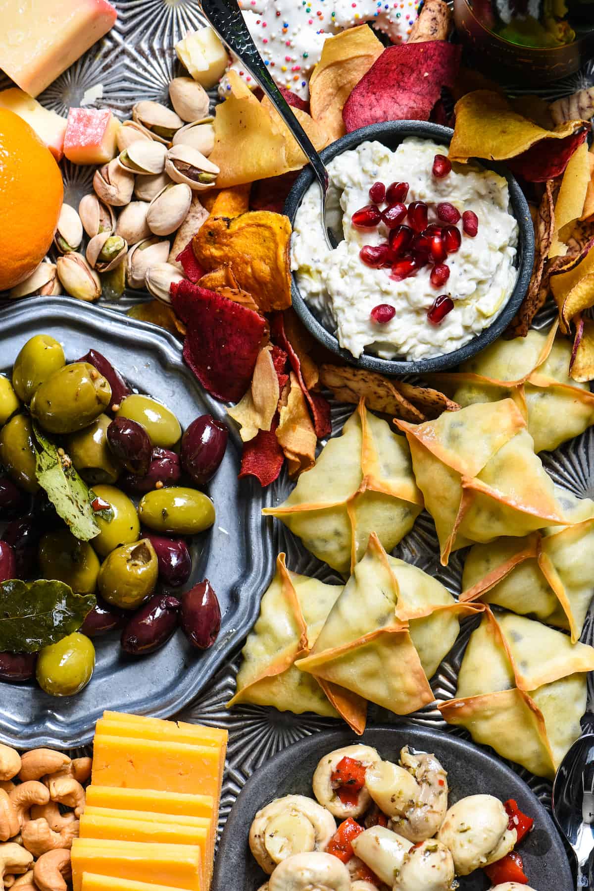 Closeup photo of platter of New Year's Eve snacks, focusing on wontons, olives and creamy dip.