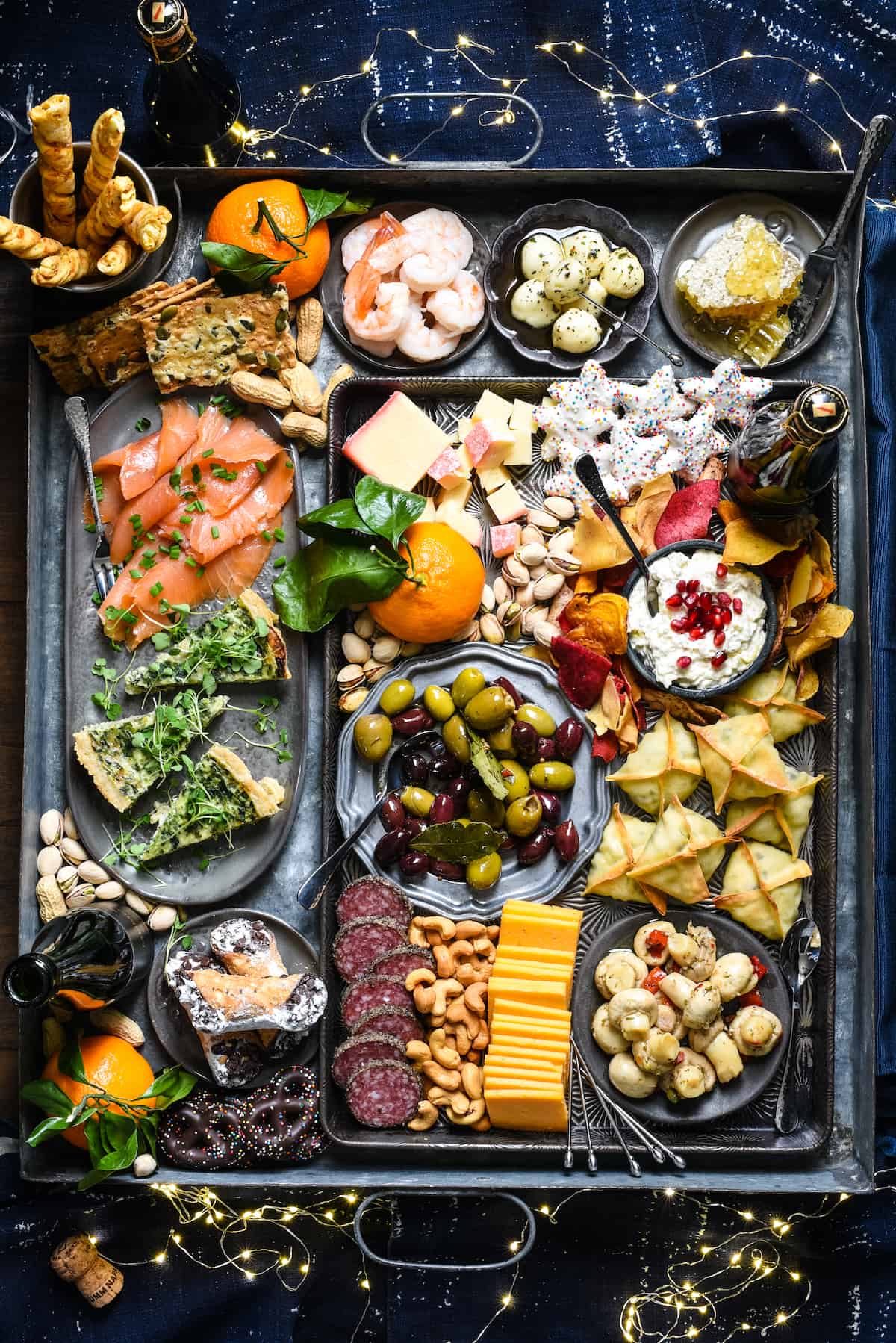 Platter filled with New Year's appetizers, including shrimp, cheese, cookies, wontons, cannoli and quiche.