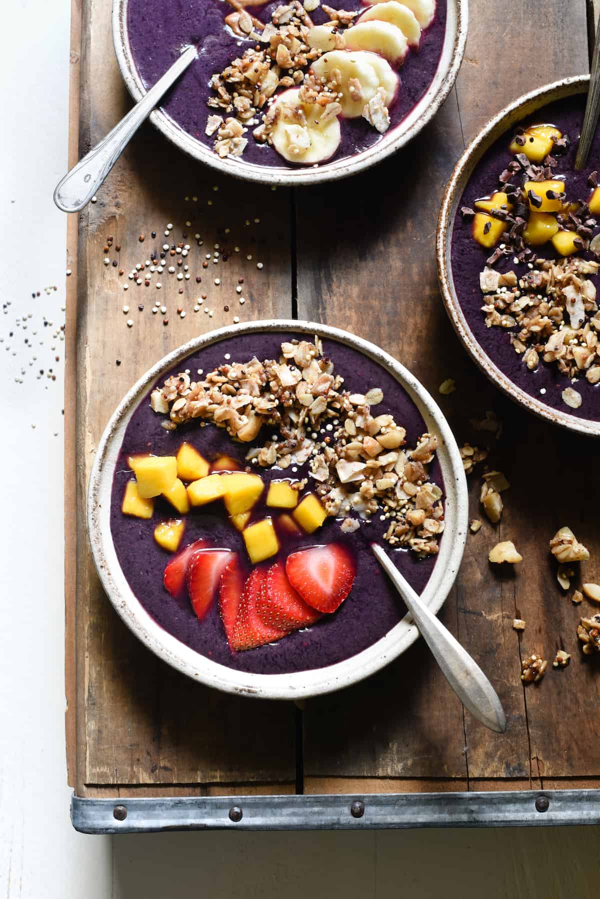 Get your day started with the powerful superfoods in these Açaí Bowls with Maple Quinoa Granola! Berry and banana smoothie bowls are topped with easy homemade granola, fresh fruit and almond butter. Naturally gluten free and vegan. | foxeslovelemons.com
