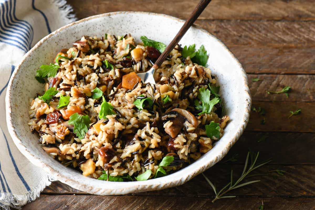 Large serving of rice for Thanksgiving in handmade pottery bowl on wooden tabletop.