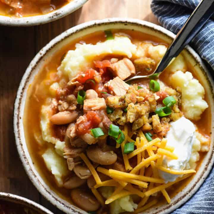 This Leftover Turkey Chili recipe lets you use up almost all of your Thanksgiving leftovers in one bowl! Easy turkey chili is spooned over mashed potatoes and topped with Crunchy Stuffing Bits! | foxeslovelemons.com