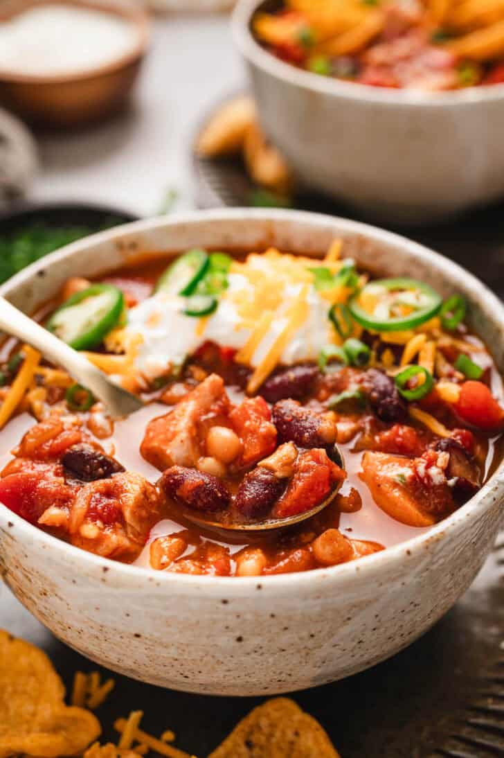 A bowl of leftover turkey chili with a spoon scooping some out.