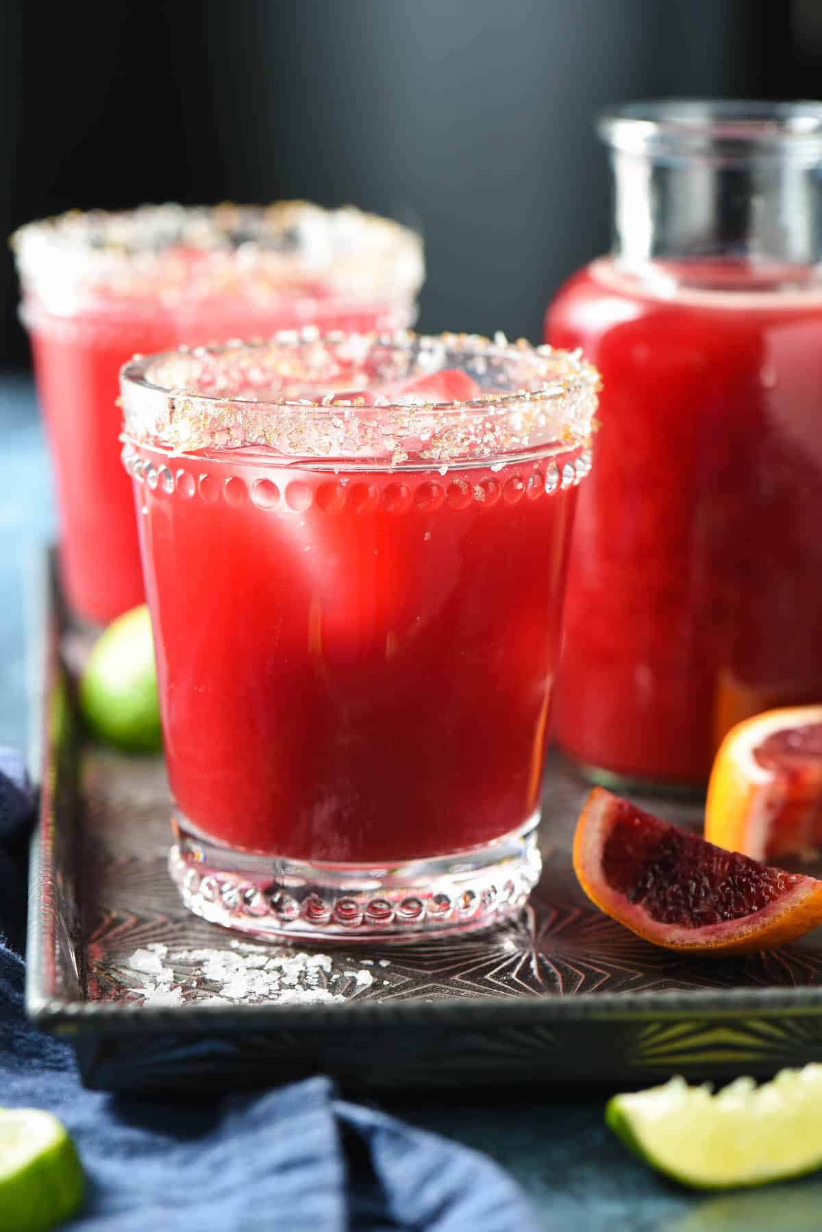 Bright red cocktail in glass garnished with salt and sugar.