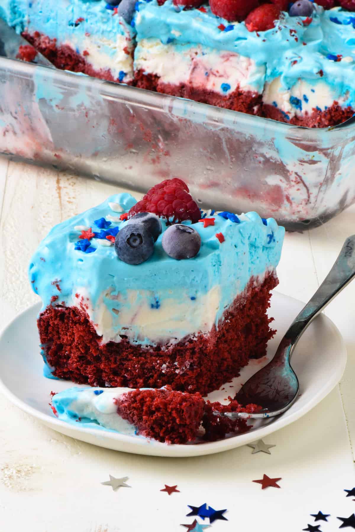 Square piece of patriotic ice cream cake on small white plate with fork. 