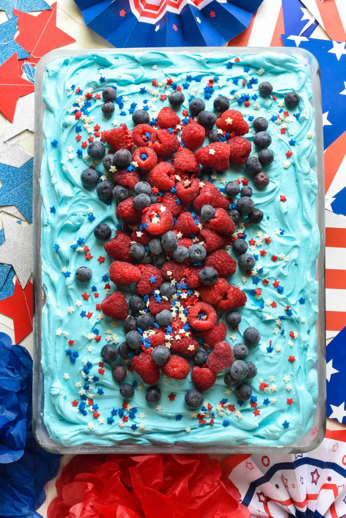 Overhead shot of patriotic ice cream cake topped with raspberries, blueberries and star sprinkles.