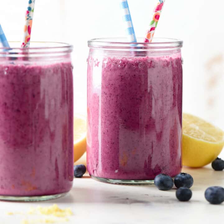 Two glass jars filled with bright purple liquid and printed paper straws.