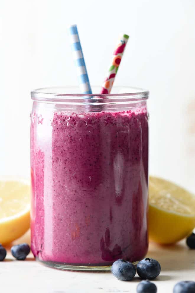 Glass jar filled with the best blueberry smoothie, with printed paper straws.