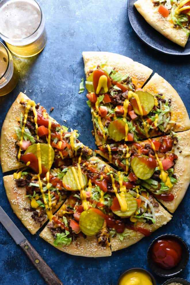 Overhead photo of savory burger flatbread cut into eight slices, missing one piece.