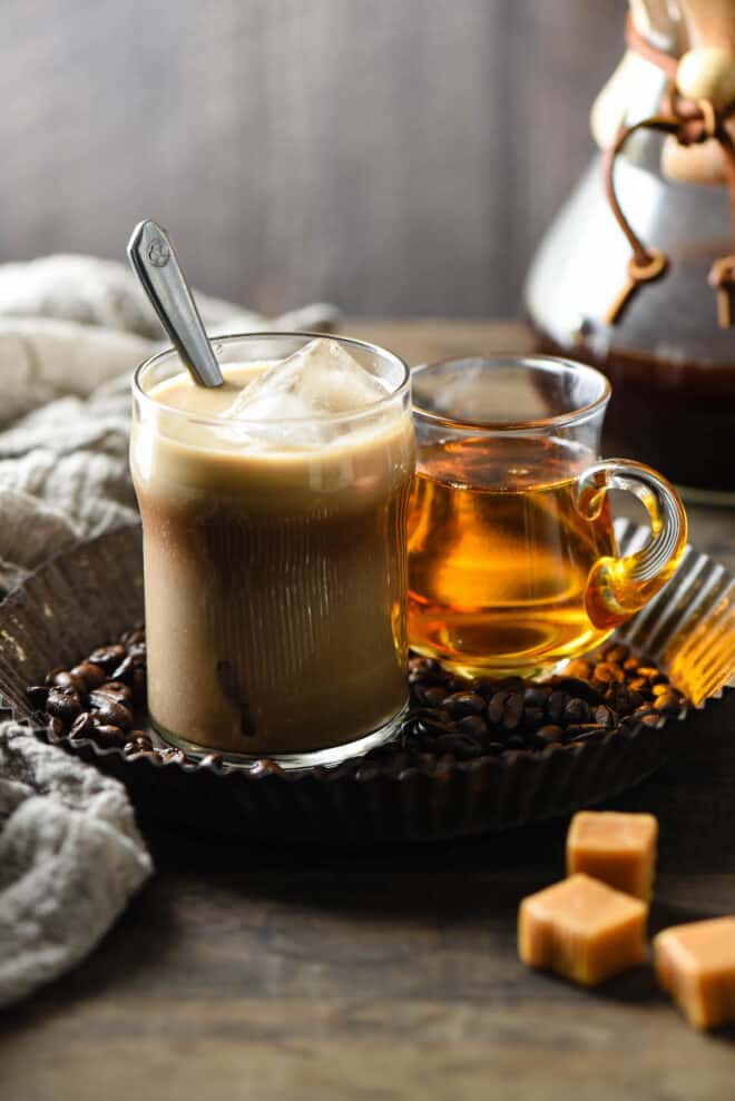 Small glass of caramel iced coffee with metal spoon.