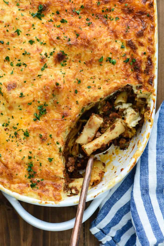 Overhead view of pastitsio casserole being spooned out to serve.