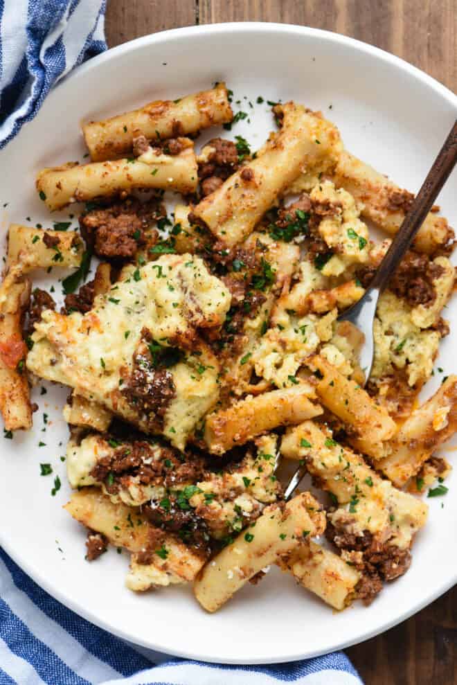 Closeup view of broken up piece of Greek lasagna - noodles, cheese and meat sauce.