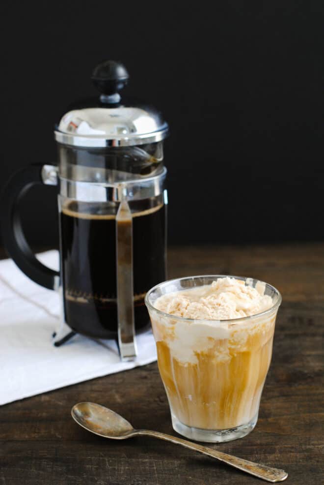 Small glass of ice cream and espresso dessert with French press, napkin and spoon.