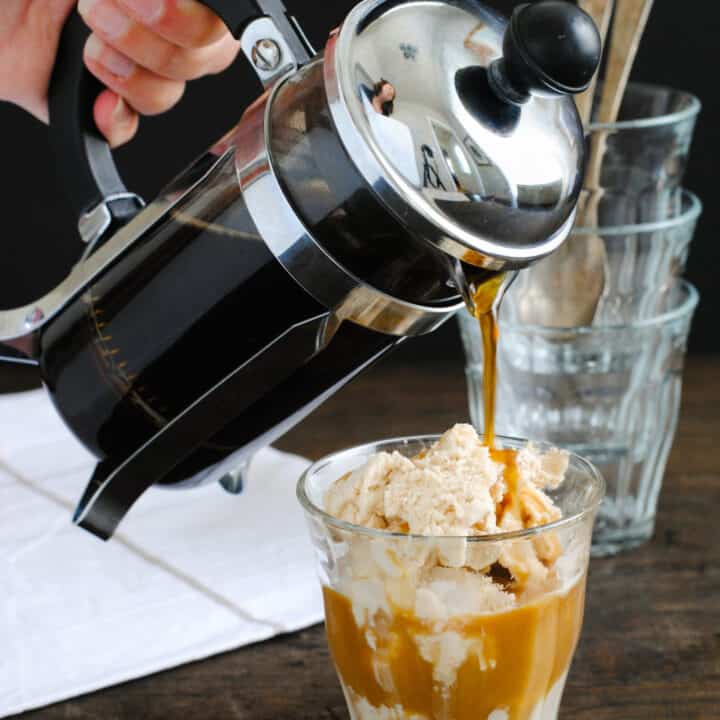Small glass of ice cream with French pressed coffee being poured over it.