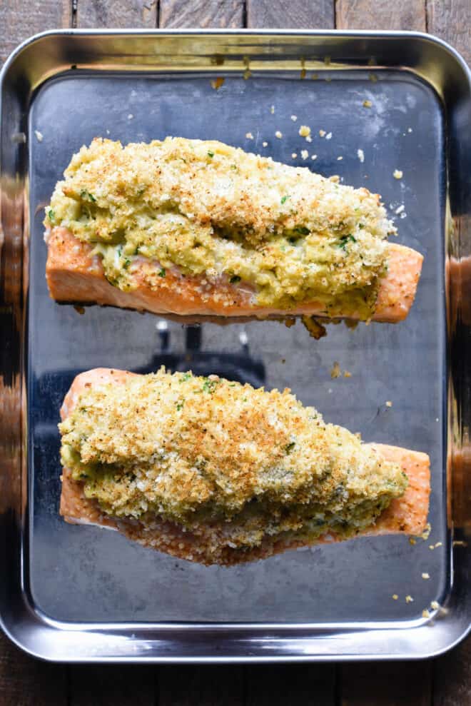 Small baking dish with two pieces of fish topped with a breadcrumb-based stuffing.